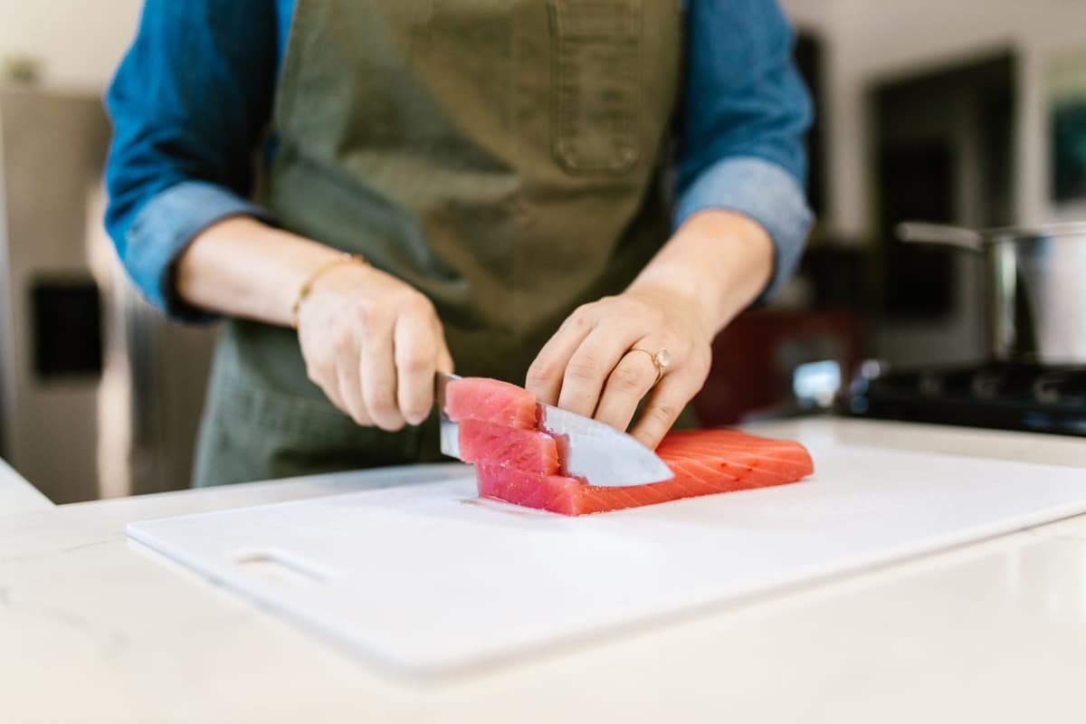 Woman slicing a fresh salmon fillet on a cutting board