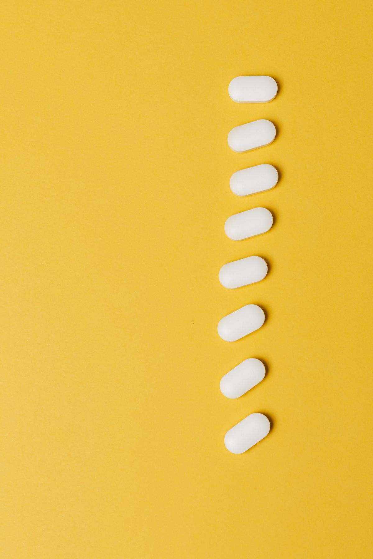 A wellness flat lay with capsules, fresh ginger, garlic and dried herbs on a marble surface